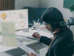 Ein Mann sitzt an einem Schreibtisch und arbeitet konzentriert an einem Computer in einem modernen Büro.