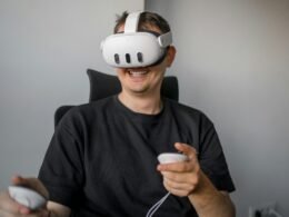 Ein Mann sitzt in einem Stuhl und hält eine Fernbedienung in der Hand, bereit zur Steuerung von Mediengeräten.