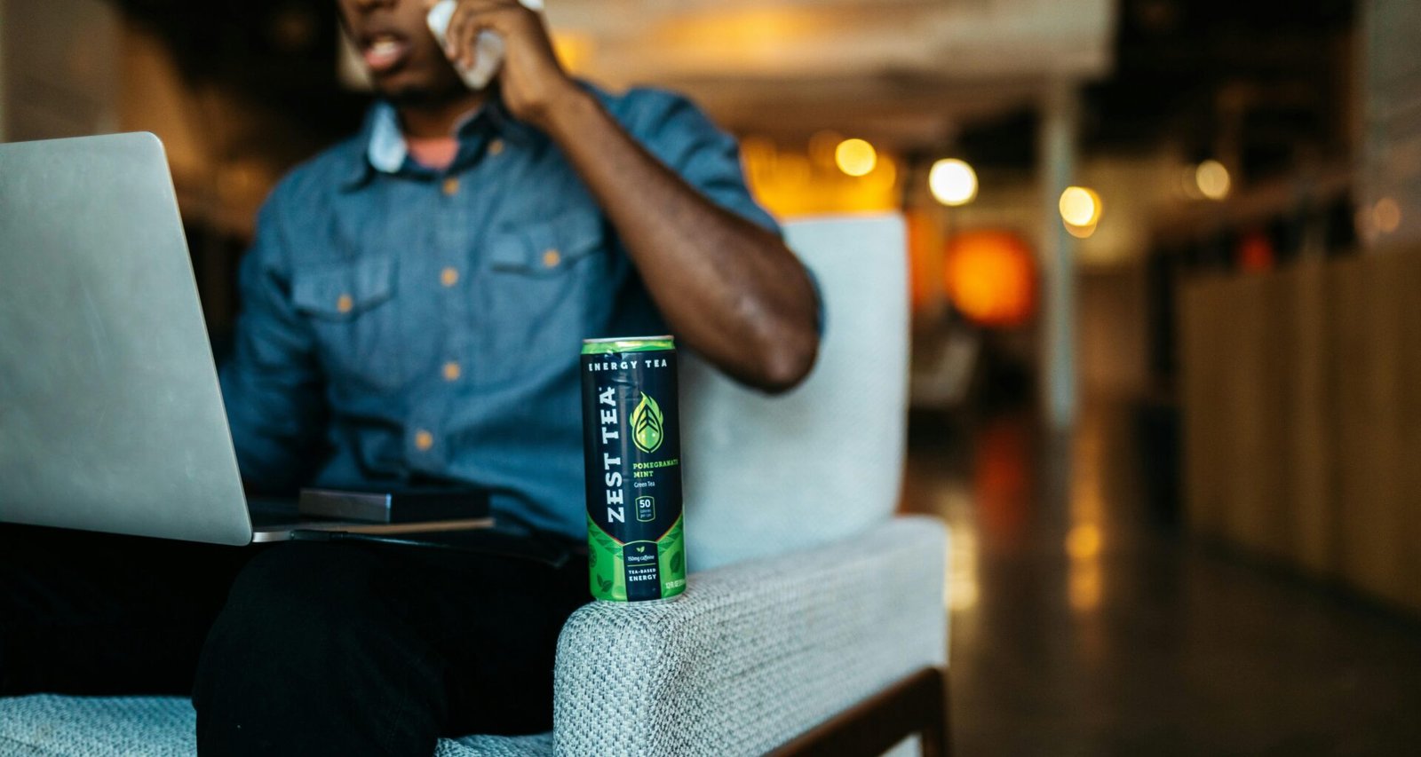 Erwachsener Mann sitzt in einem modernen Bürostuhl und spricht über sein Smartphone in einem Innenraum.