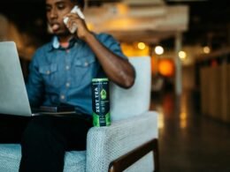 Erwachsener Mann sitzt in einem modernen Bürostuhl und spricht über sein Smartphone in einem Innenraum.