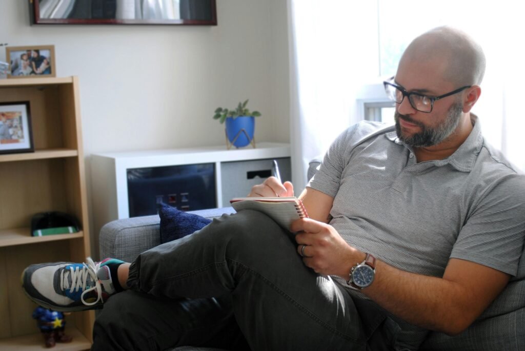 Mann sitzt auf einem grauen Sofa in einem modernen Wohnzimmer, geeignet für Themen zu Arbeit und Freizeit zu Hause