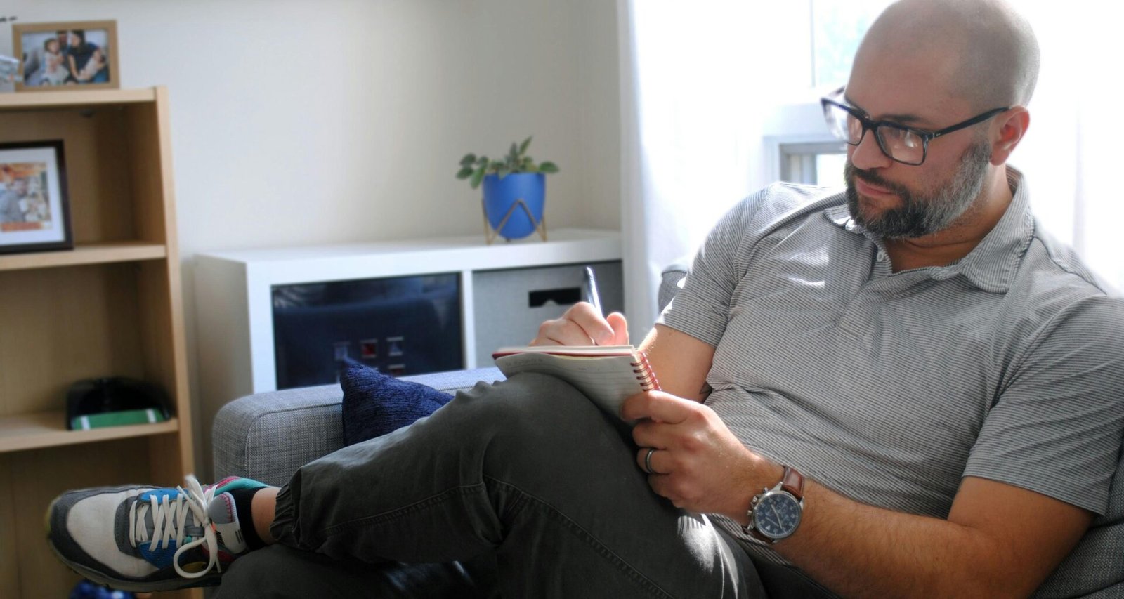 Mann sitzt auf einem grauen Sofa in einem modernen Wohnzimmer, geeignet für Themen zu Arbeit und Freizeit zu Hause