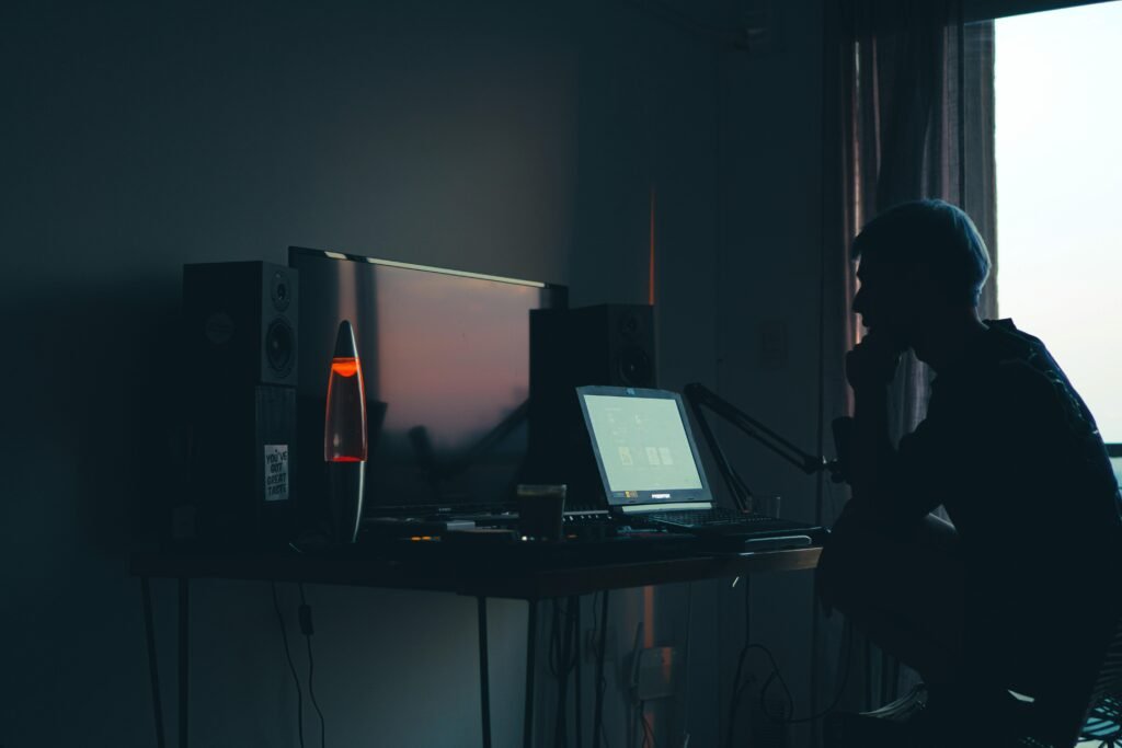Ein Mann sitzt nachts in einem dunklen Raum vor einem Computerbildschirm und arbeitet konzentriert