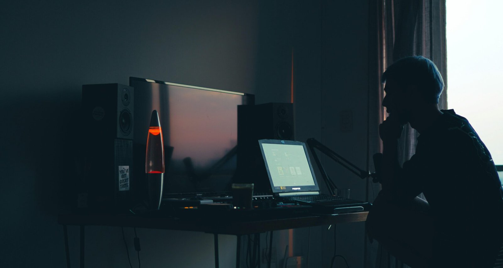 Ein Mann sitzt nachts in einem dunklen Raum vor einem Computerbildschirm und arbeitet konzentriert