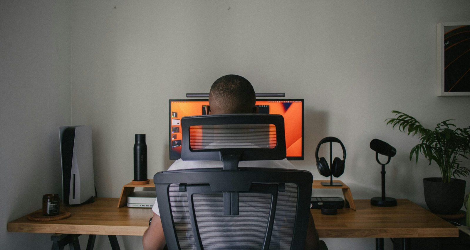 Ein Mann sitzt an einem Schreibtisch vor einem Computerbildschirm in einem modernen Arbeitsumfeld.