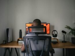 Ein Mann sitzt an einem Schreibtisch vor einem Computerbildschirm in einem modernen Arbeitsumfeld.