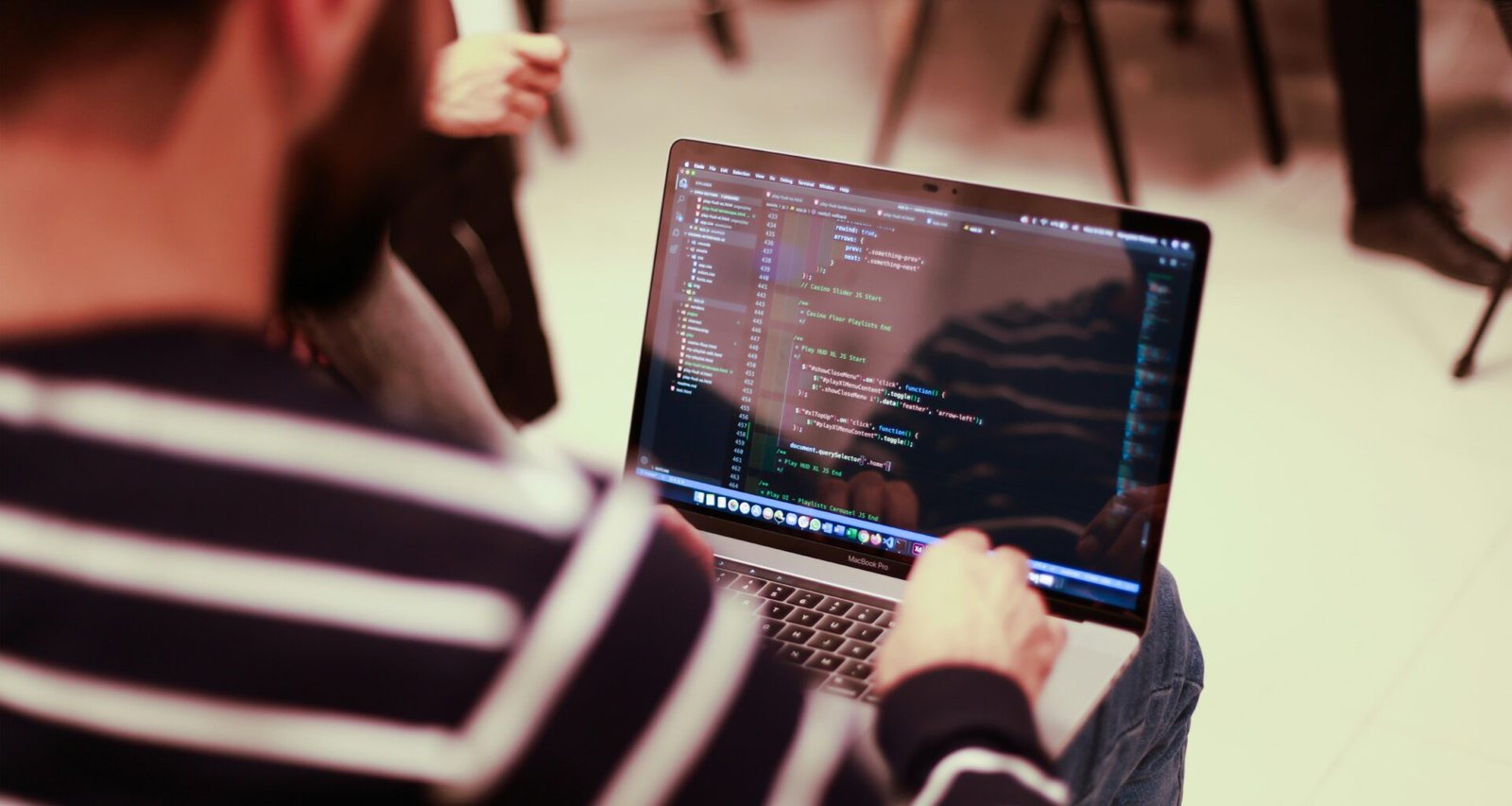 Ein Mann sitzt an einem Tisch vor einem aufgeklappten Laptop und arbeitet konzentriert am Computer