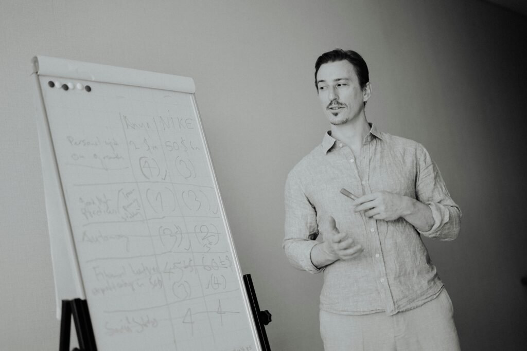 Ein Mann steht neben einem Whiteboard mit verschiedenen Notizen, ideal für Artikel über Teamarbeit oder Strategieplanung.