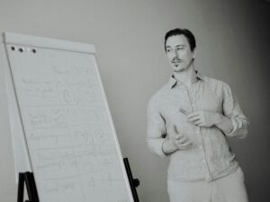 Ein Mann präsentiert Notizen auf einem Whiteboard während einer Teambesprechung im modernen Büro