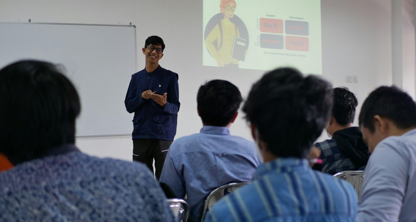Ein Mann steht vor mehreren Menschen und spricht zu einer Gruppe in einem Konferenzraum.