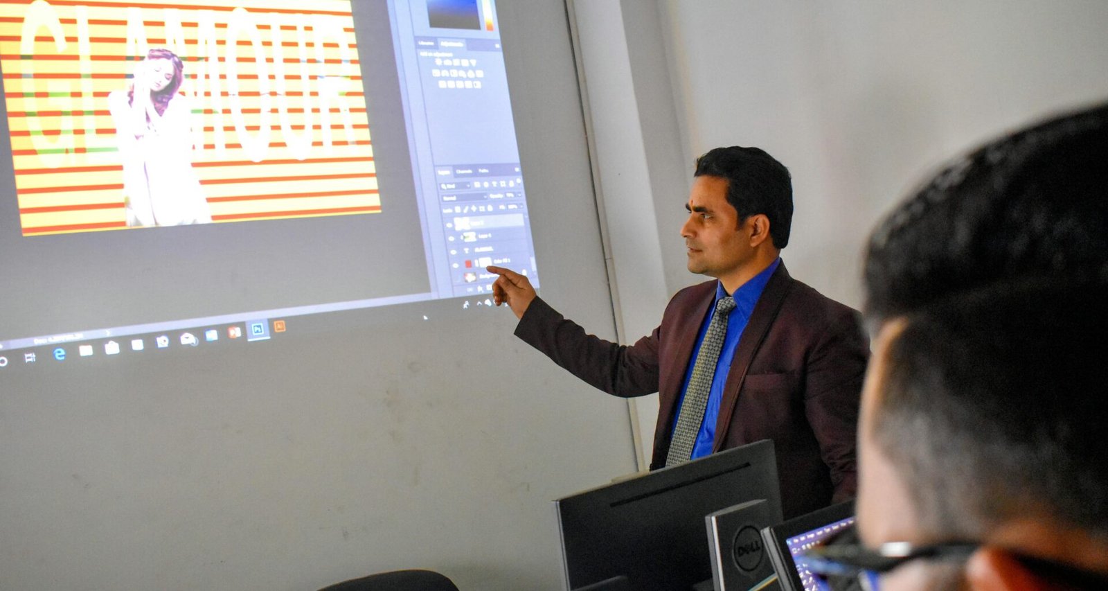 Ein Mann steht vor einer Projektionsleinwand und spricht während einer Präsentation zu seinem Publikum.