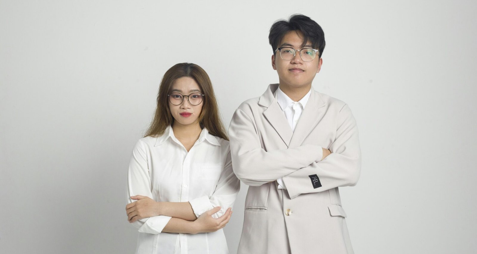 Ein Mann und eine Frau stehen nebeneinander und schauen gemeinsam in eine Richtung, beide im Business-Outfit.