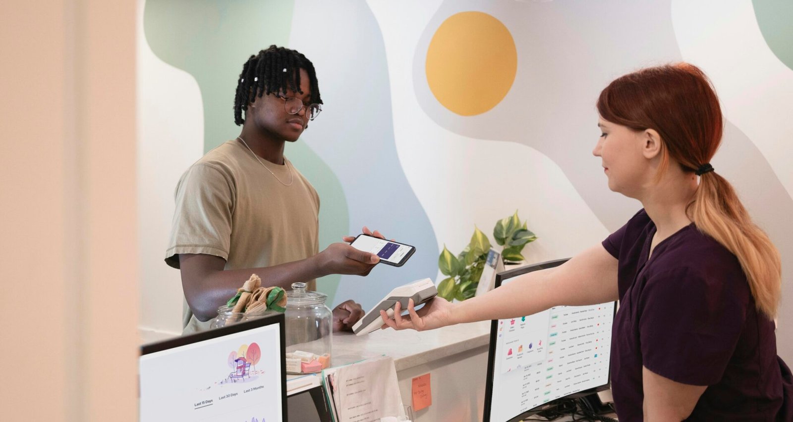 Ein Mann und eine Frau stehen gemeinsam vor einem großen Computerbildschirm in einem modernen Büro