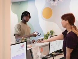 Ein Mann und eine Frau stehen gemeinsam vor einem großen Computerbildschirm in einem modernen Büro