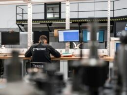 Ein Mitarbeiter sitzt an einem Schreibtisch und arbeitet konzentriert vor mehreren Computerbildschirmen im Büro.