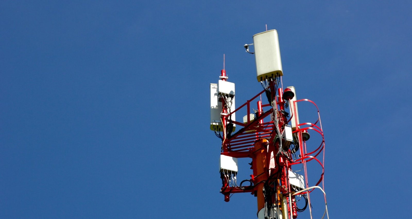 Ein Mobilfunkmast vor blauem Himmel steht im Mittelpunkt und repräsentiert zeitgemäße Kommunikationstechnologien.