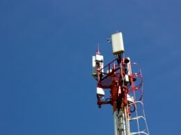 Ein Mobilfunkmast vor blauem Himmel steht im Mittelpunkt und repräsentiert zeitgemäße Kommunikationstechnologien.