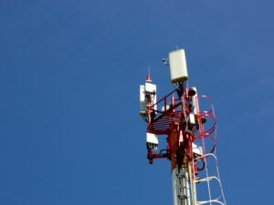 Ein Mobilfunkmast vor blauem Himmel steht im Mittelpunkt und repräsentiert zeitgemäße Kommunikationstechnologien.