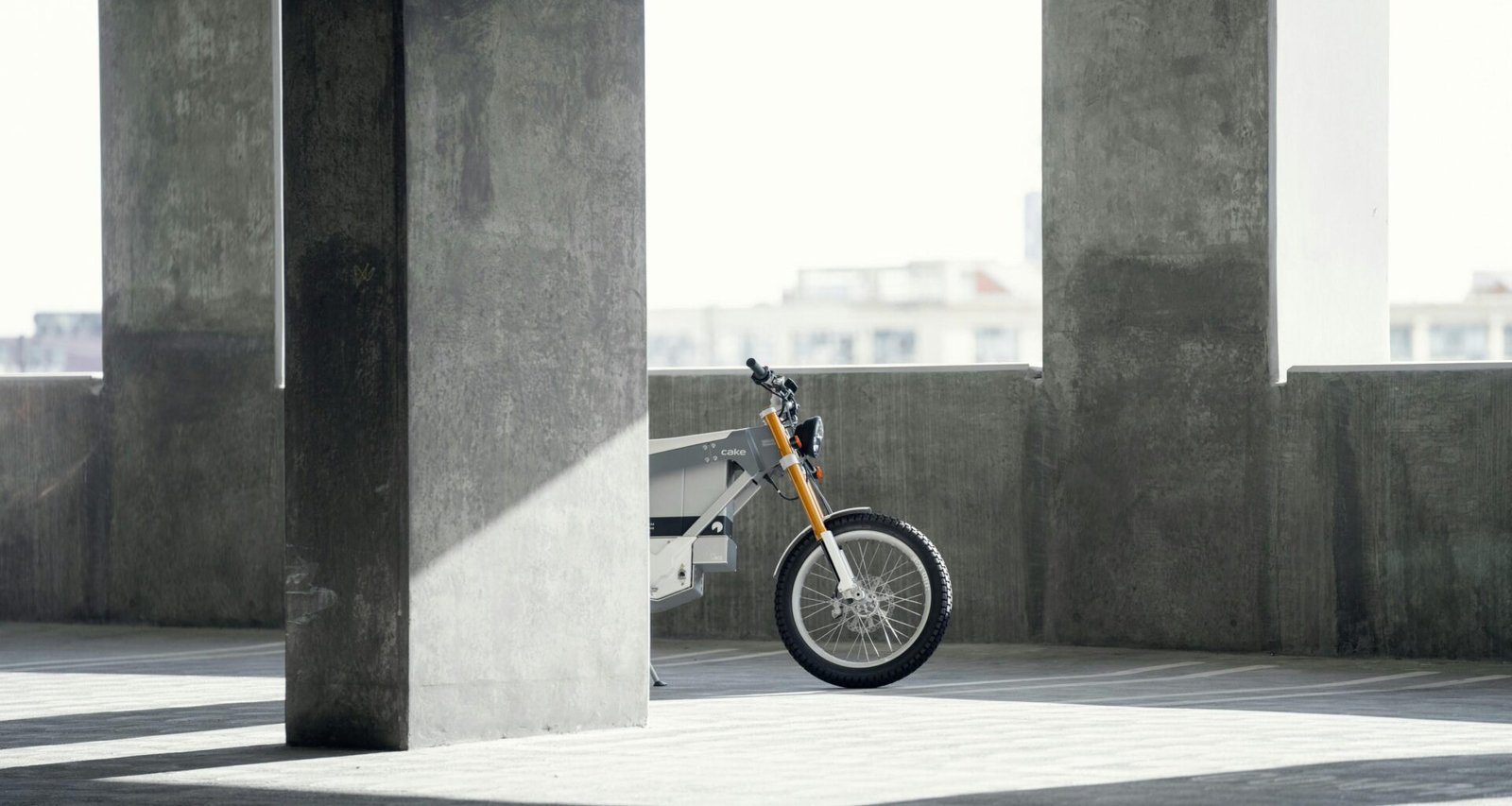 Ein Motorrad ist ordentlich in einer geräumigen, gut beleuchteten Parkgarage abgestellt, umgeben von Betonwänden und Parkbuchten.