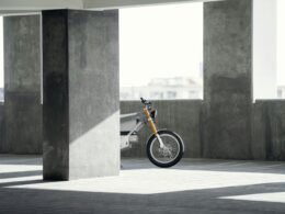 Ein Motorrad ist ordentlich in einer geräumigen, gut beleuchteten Parkgarage abgestellt, umgeben von Betonwänden und Parkbuchten.