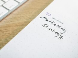 Notizblock mit handschriftlich vermerkter Marketingstrategie auf einem Schreibtisch, fokussiert auf effiziente Planung