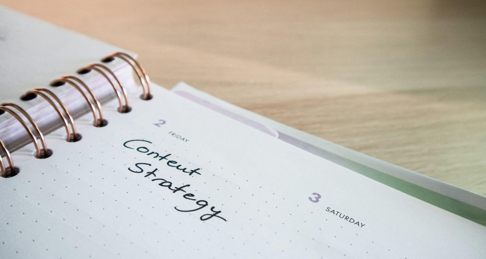 Ein Notizblock mit einem Spiralheft obenauf liegt auf einem Tisch – ideal für Notizen und Planung im Büroalltag.