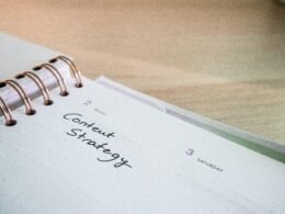 Ein Notizblock mit einem Spiralheft obenauf liegt auf einem Tisch – ideal für Notizen und Planung im Büroalltag.