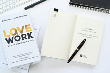 Ein aufgeklapptes Notizbuch mit einem Stift darauf neben einer Computertastatur auf einem Schreibtisch