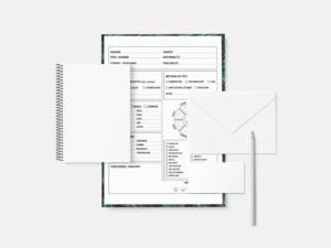 Ein aufgeschlagenes Notizbuch mit einem Kugelschreiber und Papier obenauf, arrangiert auf einem hellen Untergrund