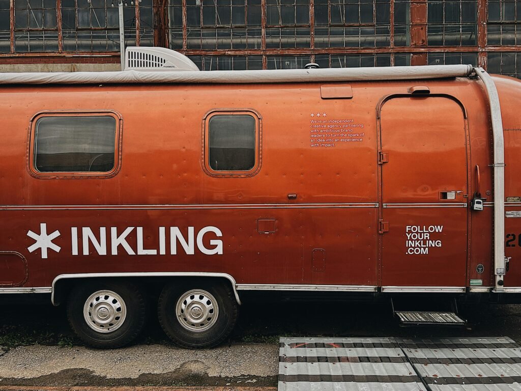 Orangefarbener Anhänger steht geparkt am Straßenrand neben einer ruhigen Straße, urbanes Umfeld, moderne Szene