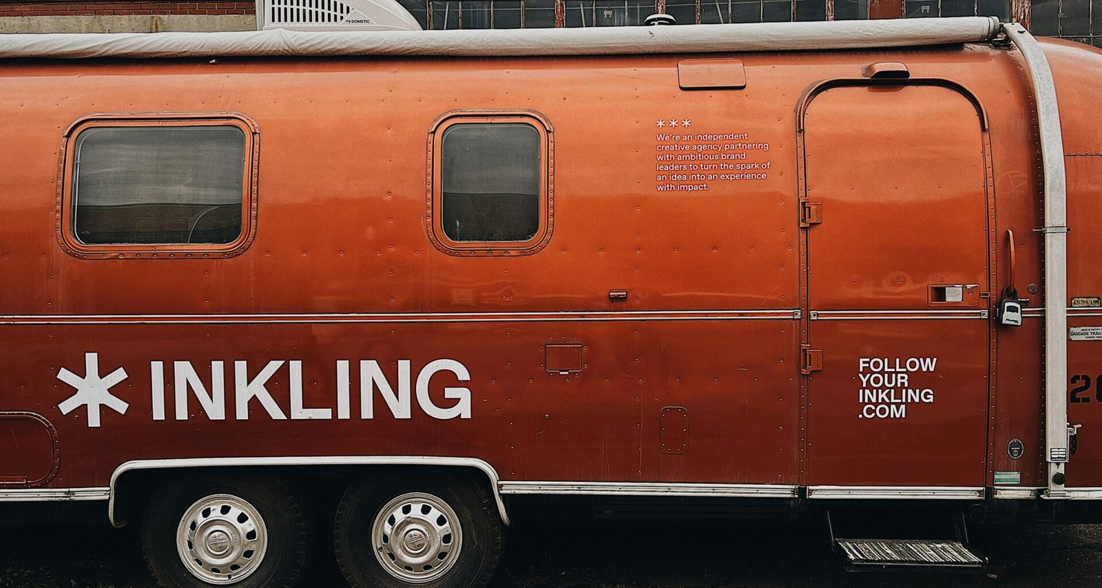 Orangefarbener Anhänger steht geparkt am Straßenrand neben einer ruhigen Straße, urbanes Umfeld, moderne Szene