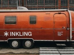 Orangefarbener Anhänger steht geparkt am Straßenrand neben einer ruhigen Straße, urbanes Umfeld, moderne Szene