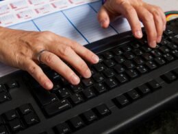 Zwei Hände tippen auf einer Computertastatur und stehen für digitale Arbeit am modernen Arbeitsplatz.