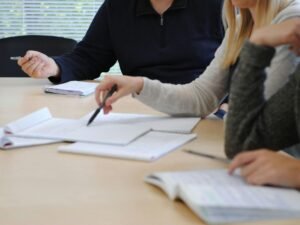 Mehrere Personen sitzen an einem gemeinsamen Tisch und arbeiten zusammen an einem Projekt in einem Büro