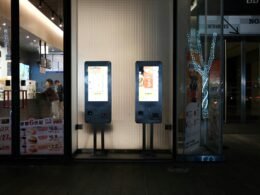 Zwei Maschinen stehen nebeneinander im Innenbereich eines Gebäudes. Moderne Technik, industrielle Umgebung, passend für Technologieartikel.