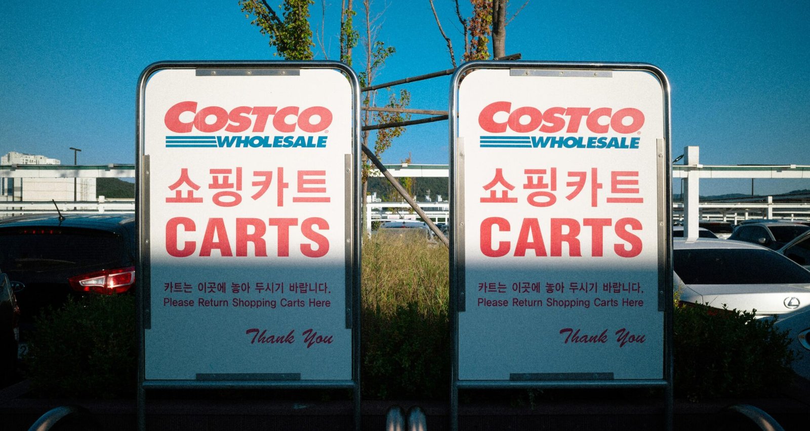 Mehrere Verkehrsschilder vor geparkten Autos in einer urbanen Umgebung, deutliche Sicht auf Fahrzeuge und Schilder.