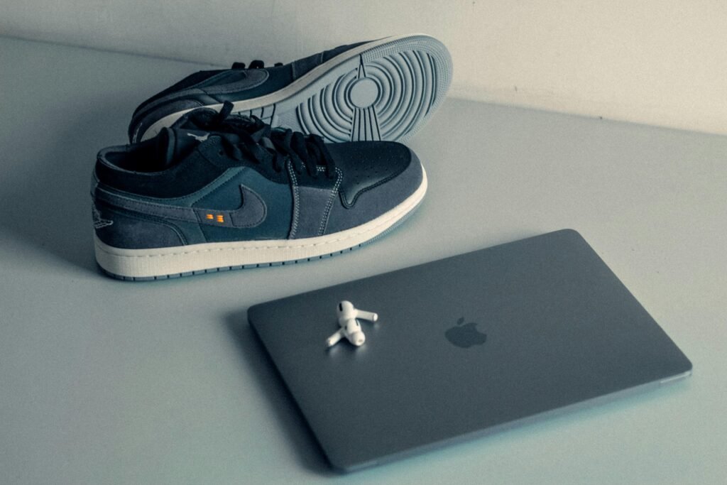 Ein Paar Schuhe steht neben einem aufgeklappten Laptop auf einem Tisch in einer modernen Arbeitsumgebung.