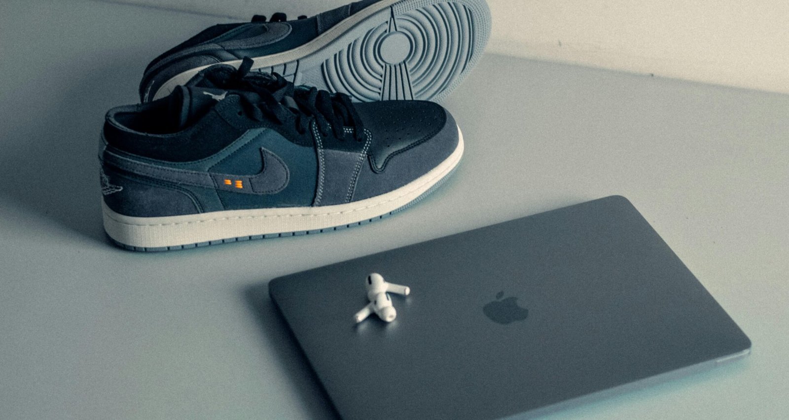 Ein Paar Schuhe steht neben einem aufgeklappten Laptop auf einem Tisch in einer modernen Arbeitsumgebung.