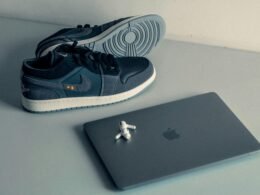 Ein Paar Schuhe steht neben einem aufgeklappten Laptop auf einem Tisch in einer modernen Arbeitsumgebung.