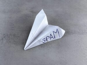 Ein Papierflieger mit dem Wort Spam darauf, symbolisiert unerwünschte E-Mail-Nachrichten im digitalen Marketing.
