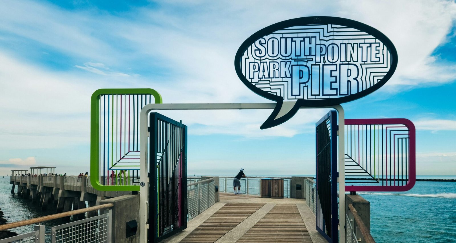 Ein langer Pier mit einem Hinweisschild 'South Point Pier', der gerade ins Meer hineinragt, bei Tageslicht fotografiert