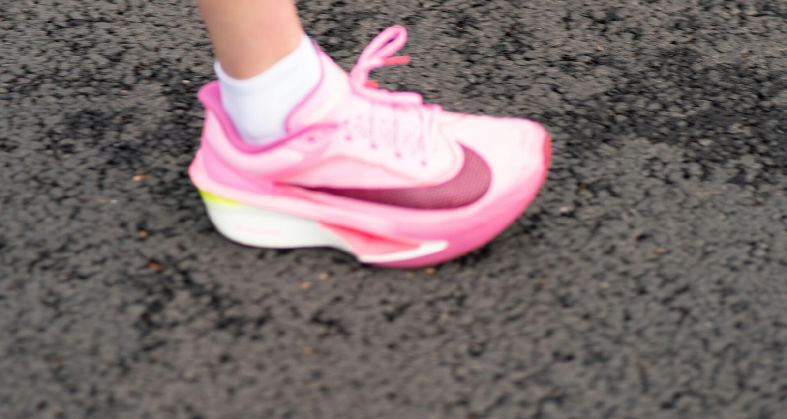 Ein einzelner pinker Sportschuh steht auf einem dunklen Untergrund und hebt sich durch sein modernes Design hervor.