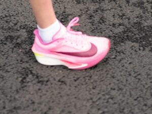 Ein einzelner pinker Sportschuh steht auf einem dunklen Untergrund und hebt sich durch sein modernes Design hervor.