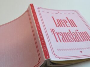 Ein pinkes Buch mit rotem Umschlag liegt auf einem weißen Hintergrund und sorgt für klaren, modernen Kontrast.