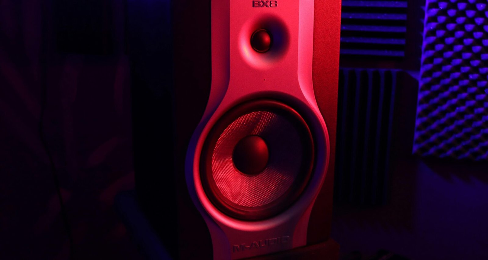 Roter und schwarzer Lautsprecher auf einem Schreibtisch, modernes Audio-Equipment für das Büro oder Homeoffice