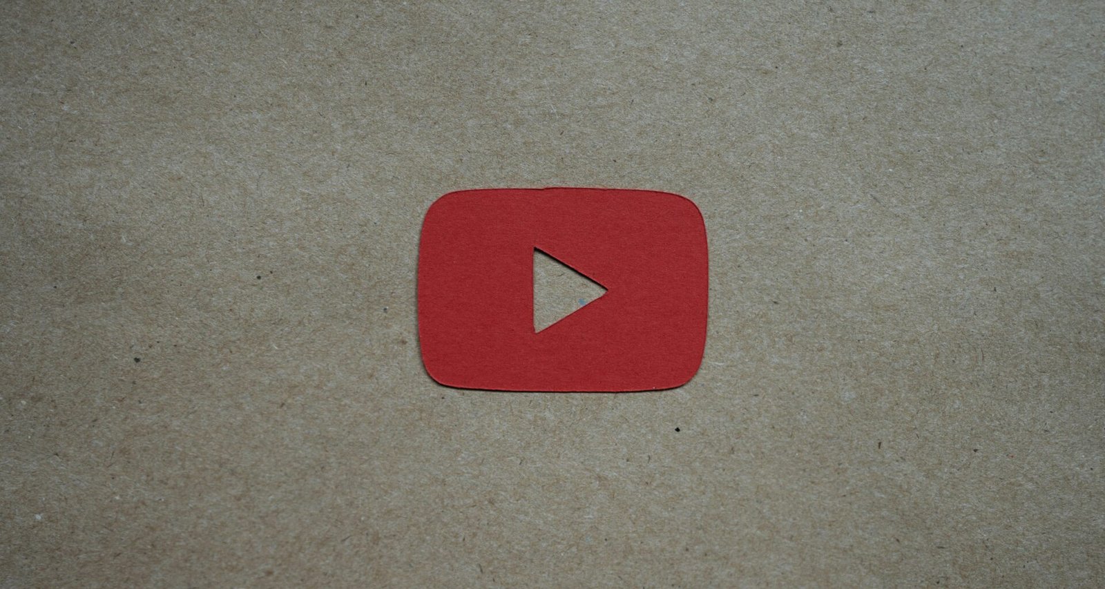 Ein roter Play-Button liegt auf einem weißen Blatt Papier und steht symbolisch für digitale Videoinhalte und Online-Marketing.