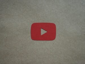 Rotes Play-Symbol liegt zentral auf einem weißen Blatt Papier und steht für digitale Medieninhalte.