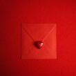 Roter Umschlag mit einem Herzsymbol in der Mitte, fotografiert auf hellem Untergrund, geeignet für Themen zur digitalen Kommunikation