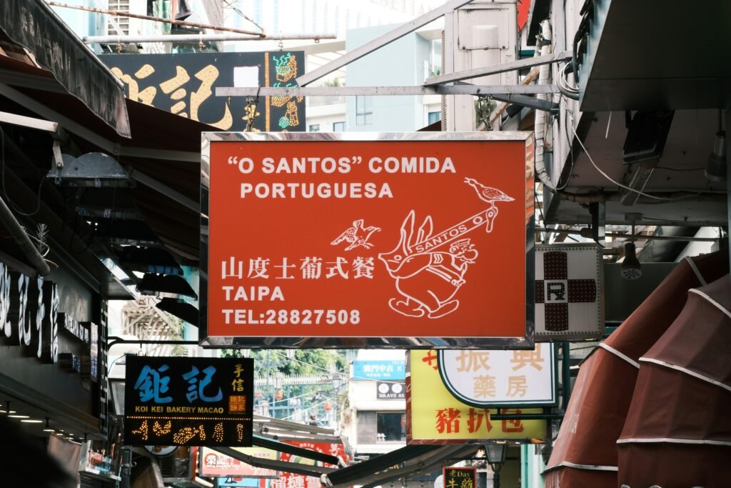 Rotes Schild, das von der Seite eines Gebäudes hängt, urbanes Detail im Straßenbild aus der Perspektive betrachtet