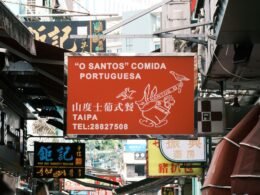 Seitlich montiertes rotes Schild an einem Gebäude, als Symbol für ein urbanes Umfeld in einer modernen Stadt